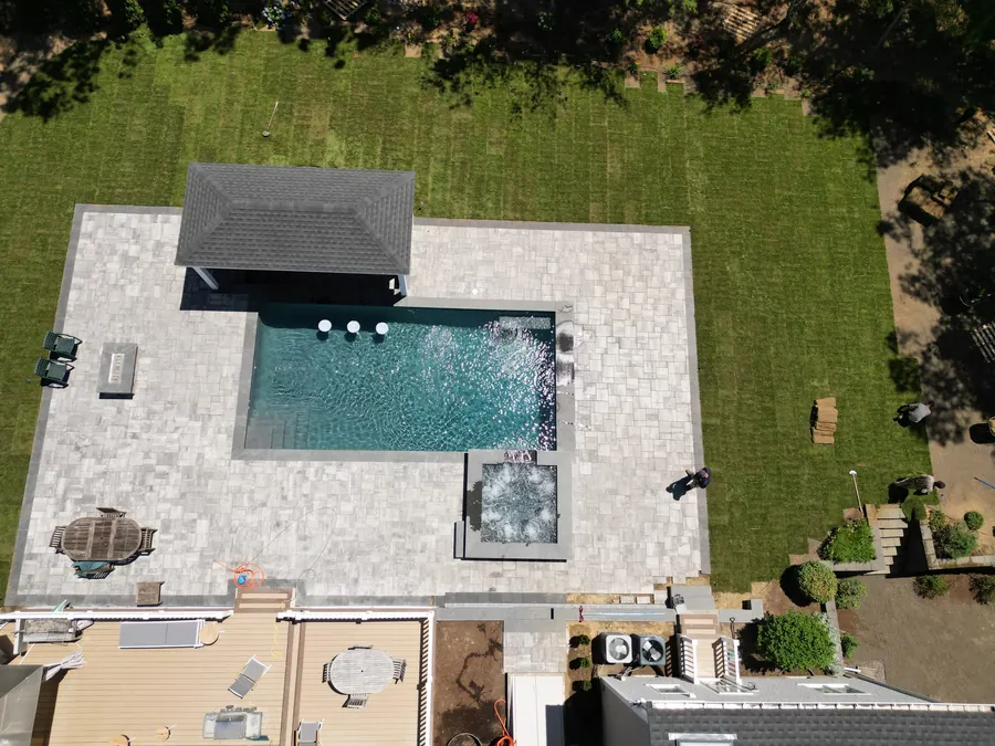 Aerial view of a pool with a cabana, spa and travertine patio
