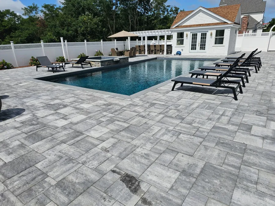 Pool with loungers in front of a white pool house