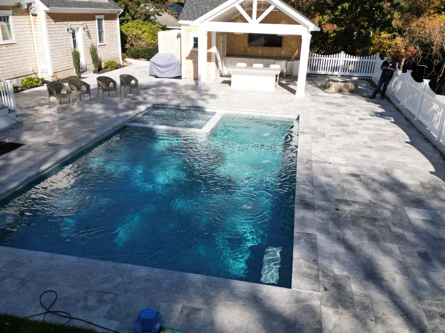 New pool in Harwich Port, MA with an attached spa, travertine deck and a covered outdoor kitchen pavilion