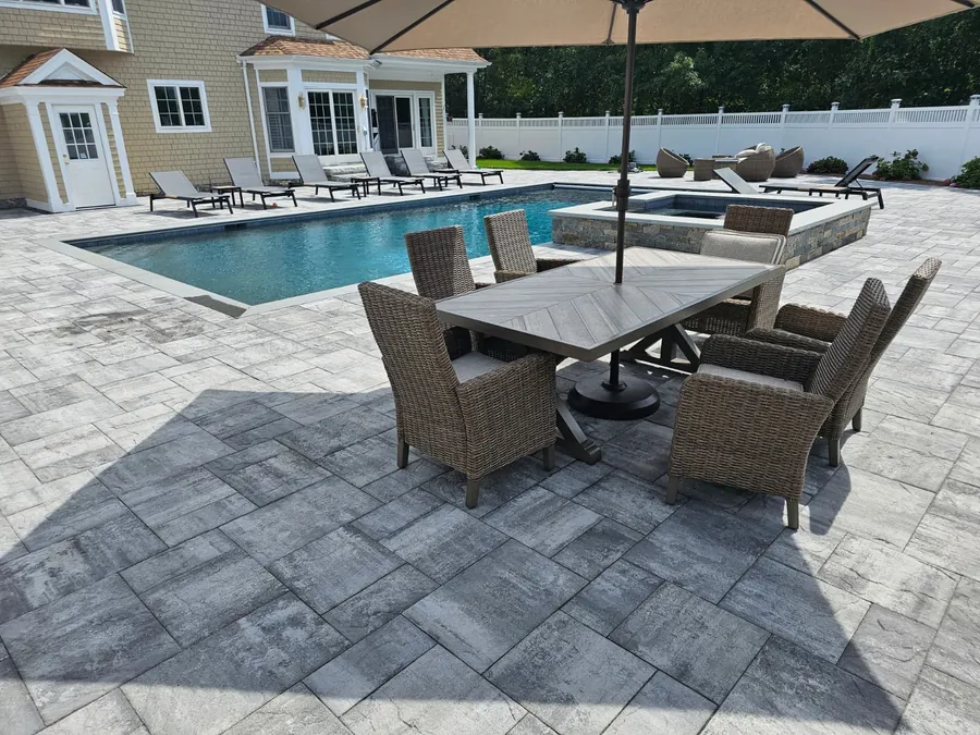 Outdoor dining set on the paver deck beside the pool