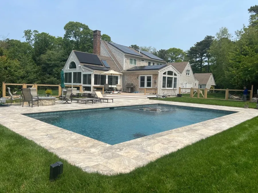 Pool with a travertine deck surrounded by lawn