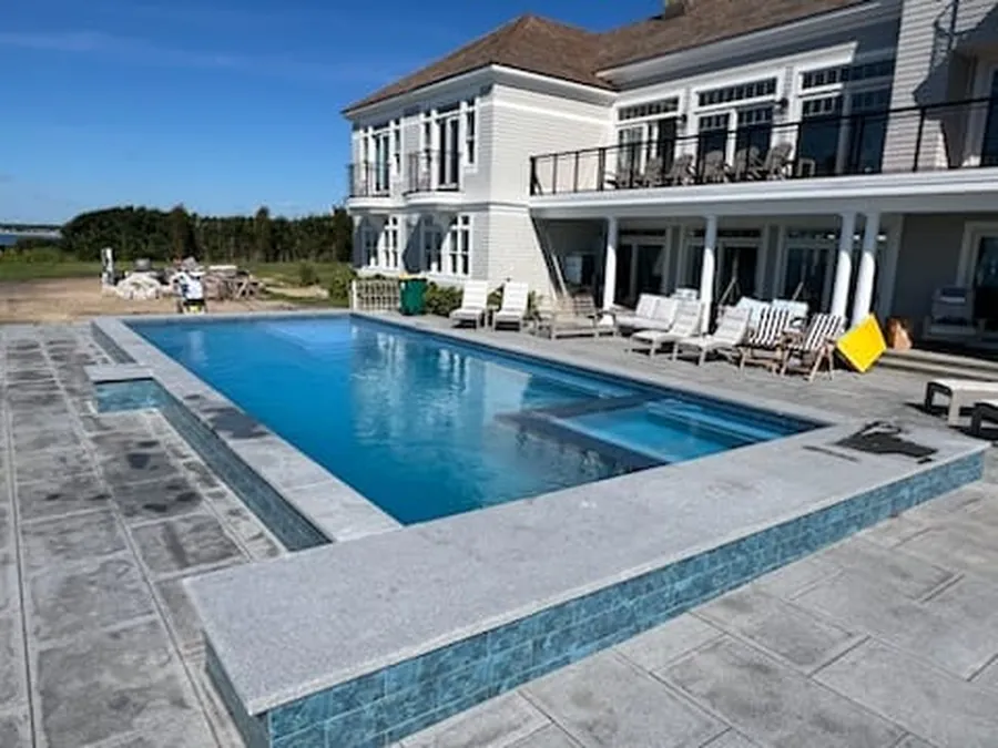 Finished pool with a glass tile edge in front of a waterfront home