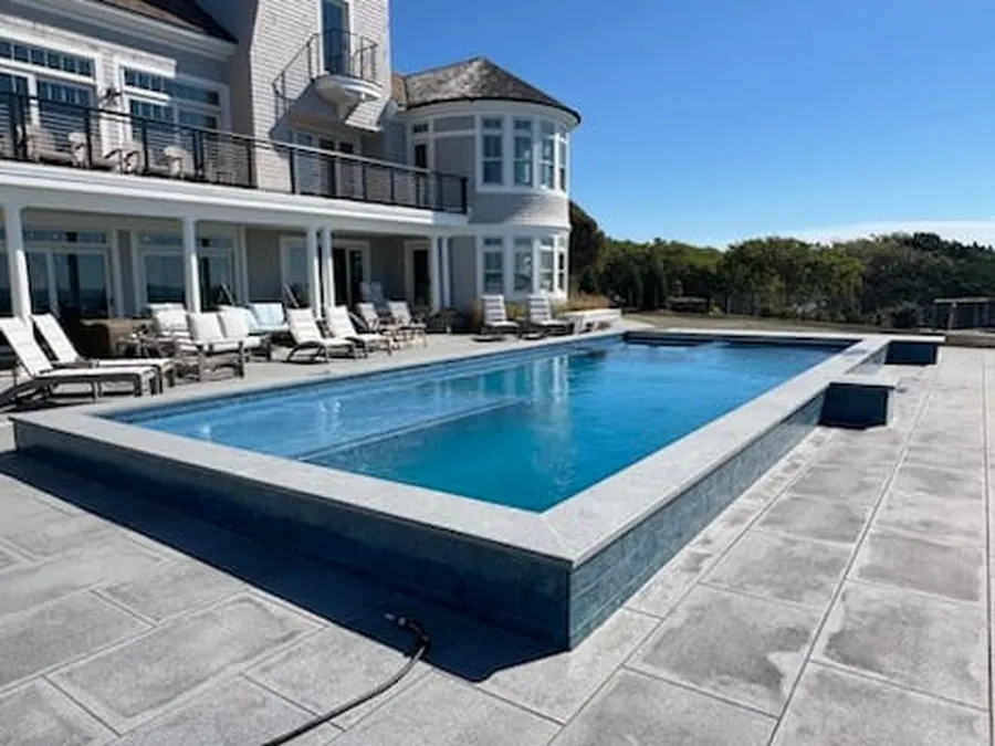 Raised-edge pool with a glass tile band in front of a waterfront home